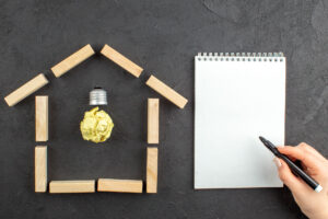 Haus aus Holzblöcken mit Glühbirne als Symbol für Geschäftsidee und Planung