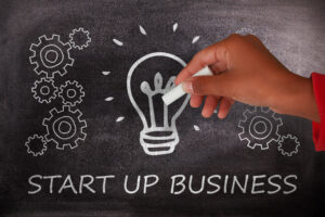 Hand zeichnet Glühbirne und Zahnräder auf Tafel mit Text Start Up Business